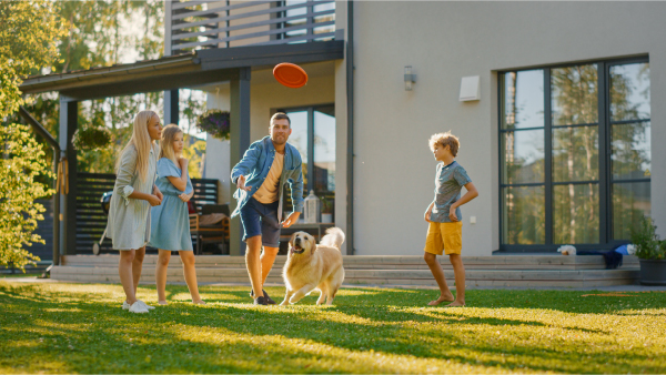 une famille joue avec son chien dans un jardin en vacance